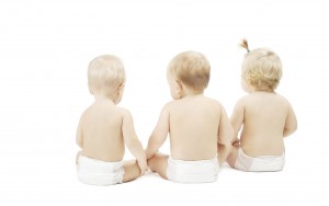 Baby friends in diapers sitting over white isolated background.